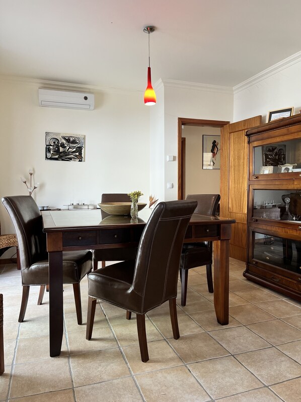 Un coin repas avec une table et des chaises en bois, un luminaire suspendu et des œuvres d’art accrochées aux murs.