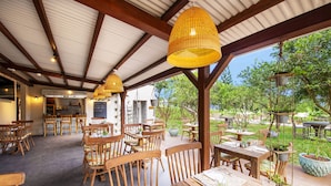 An outdoor dining area with wooden tables and chairs, a covered roof, and potted plants. - Kaz'alala Hosted B&B (Bel Ombre)