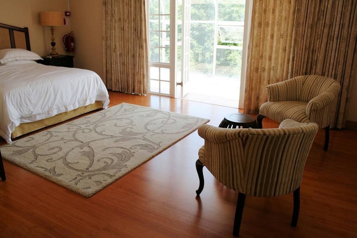 Una habitación de hotel con cama, una silla, una mesita y vistas a través de un ventanal.
