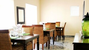 A dining area with marble flooring, wooden dining tables and chairs, and a green vase on one table. - The WhiteHouse B&B (Westville)
