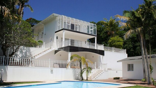 A two-story house with a balcony, a swimming pool, and a white fence. - The WhiteHouse B&B (Westville)