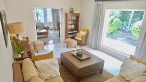 A living room with a sofa, ottoman, and a bookshelf. - The WhiteHouse B&B (Westville)