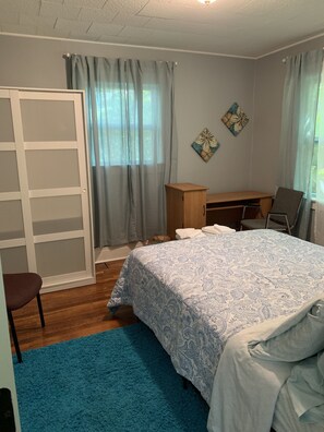 Une chambre à coucher avec un lit, un bureau, une chaise, une armoire et un tapis bleu.