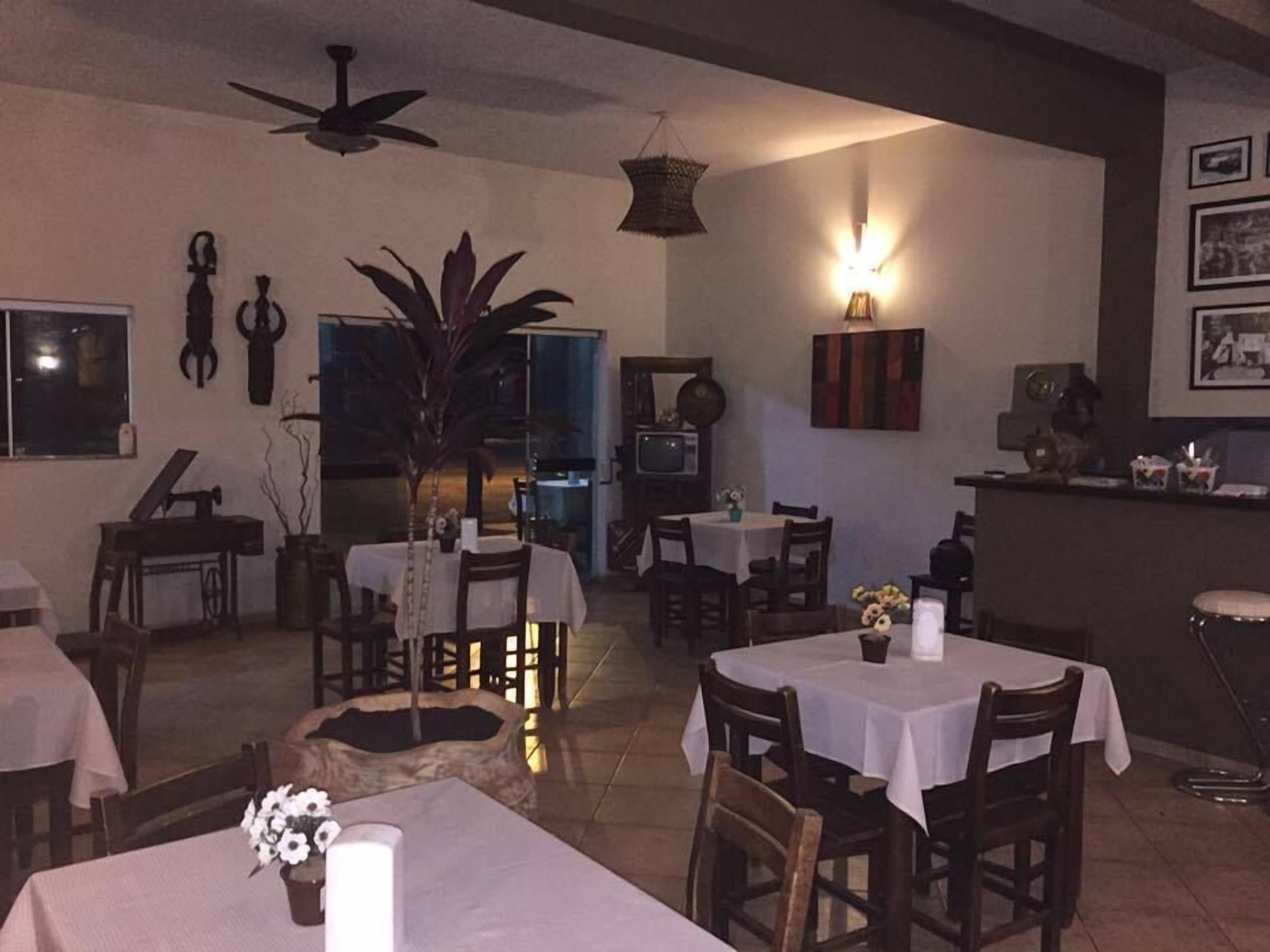 A dining area with multiple tables and chairs, a ceiling fan, and a television.