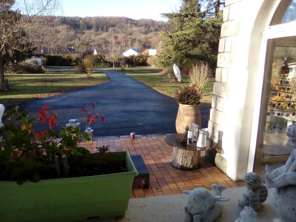 A driveway leading to a house with a garden, a patio with a table and chairs, and a display of glassware.