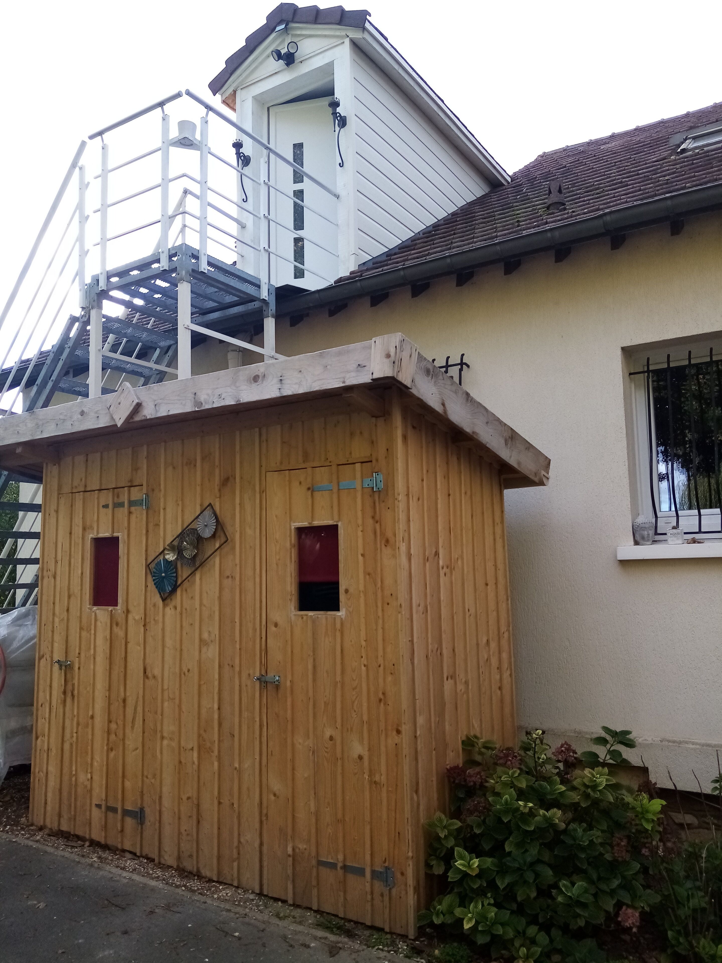 Una estructura de madera con una escalera metálica que conduce a un edificio blanco con tejado de tejas.