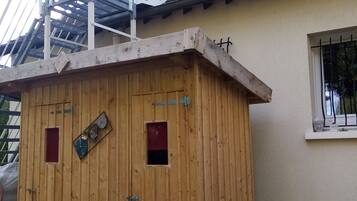 Una estructura de madera con una escalera metálica que conduce a un edificio blanco con tejado de tejas.