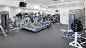 Ein Fitnessstudio mit Laufbändern, Crosstrainern und Gewichten.