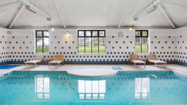 Ein Innenpool mit klarem, blauen Wasser, umgeben von gefliesten Wänden und Fenstern.