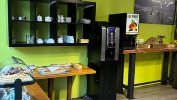 Um café com parede verde, um letreiro com os dizeres "LONDON PARIS NEW YORK", uma máquina de café e uma vitrine com diversos itens.