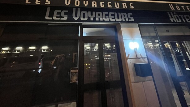 Un hotel llamado "Les Voyageurs" con un letrero sobre la entrada.