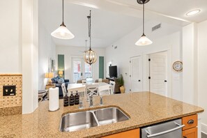 A kitchen with granite countertops, stainless steel sinks, and pendant lighting.