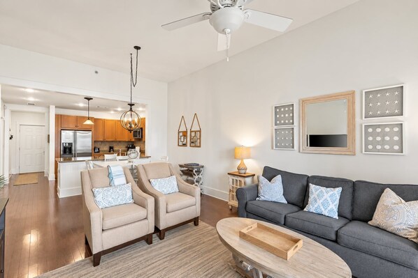 A modern living room with a grey sofa, beige armchairs, and a wooden coffee table.