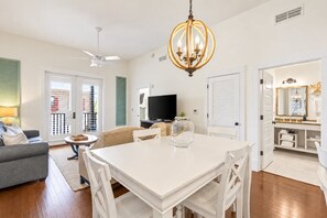 Un salon bien éclairé, comprenant une table à manger, un canapé, un téléviseur et un ventilateur de plafond.
