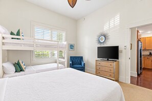 A bedroom with bunk beds, a television, a dresser, and a chair.