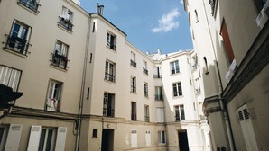 A narrow street between buildings with multiple windows and balconies.