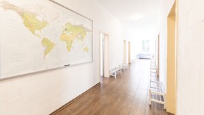 A hallway with a large world map on the wall, wooden flooring, and white walls. - Yellow Inn (St. Gallen)