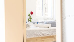 A bedroom with a bed, a window, and a red rose. - Yellow Inn (St. Gallen)