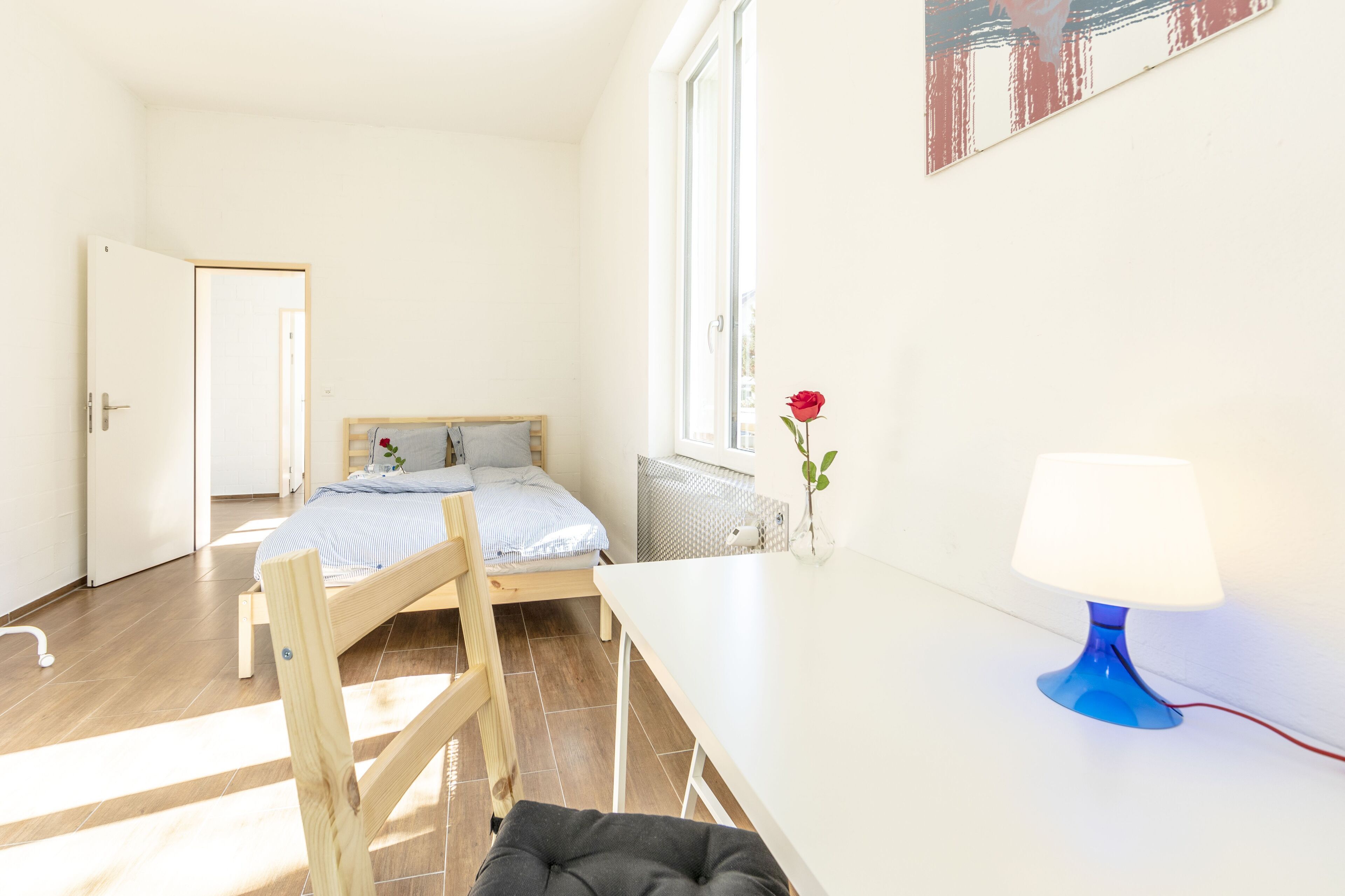 Ein kleiner, heller Raum mit einem Bett, einem Schreibtisch und einem Fenster.