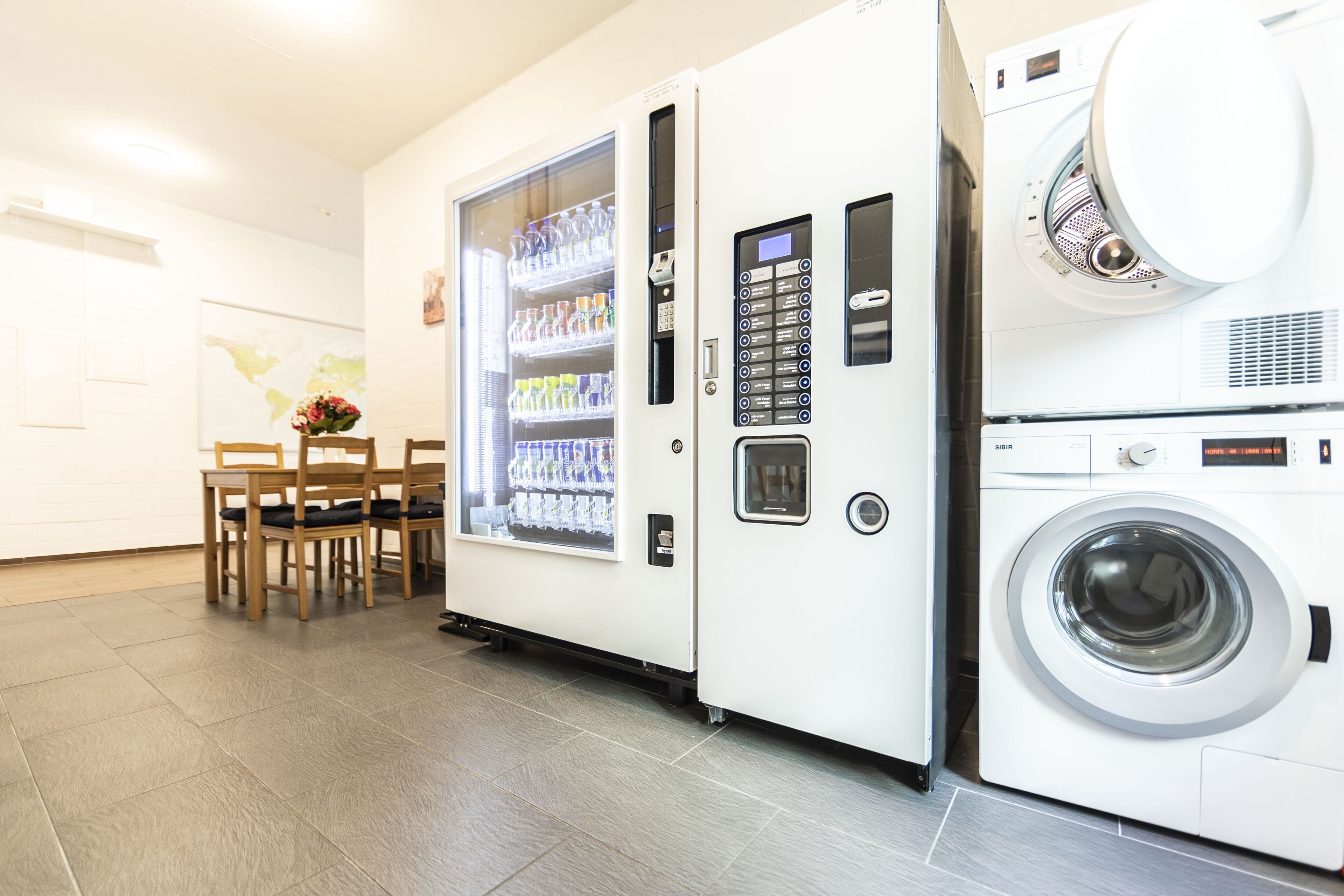 A laundry room with a vending machine and a washing machine.