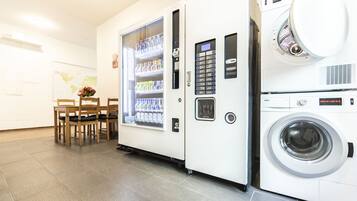 A laundry room with a vending machine and a washing machine.