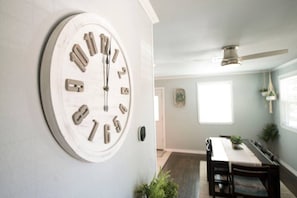Ein Essbereich mit Tisch und Stühlen, einer Wanduhr und einem Deckenventilator.