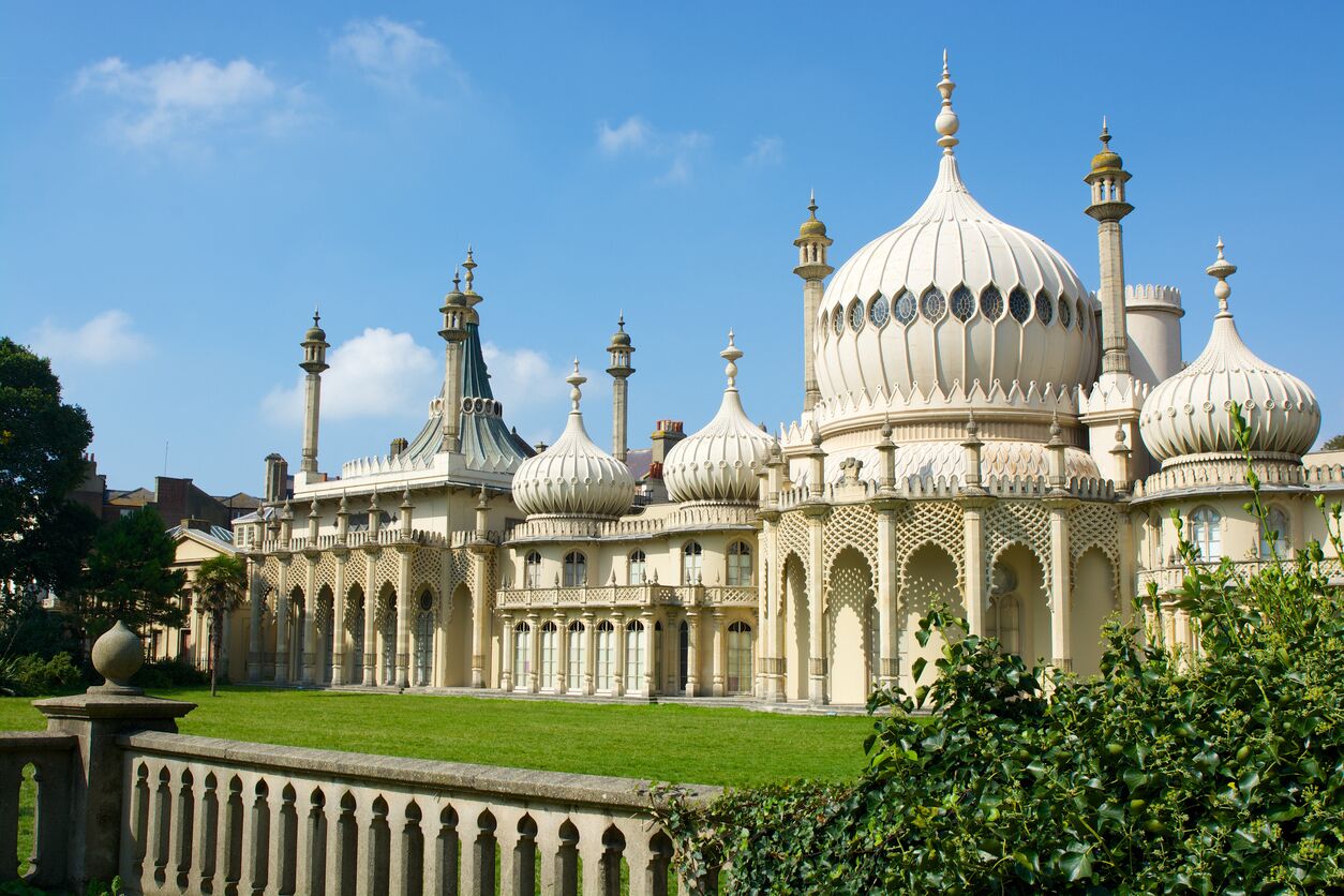 A grand, ornate building with multiple domes and minarets, surrounded by a well-maintained lawn.