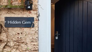 Et skilt med teksten 'Hidden Gem' på en væg med struktur og en mørk trædør.