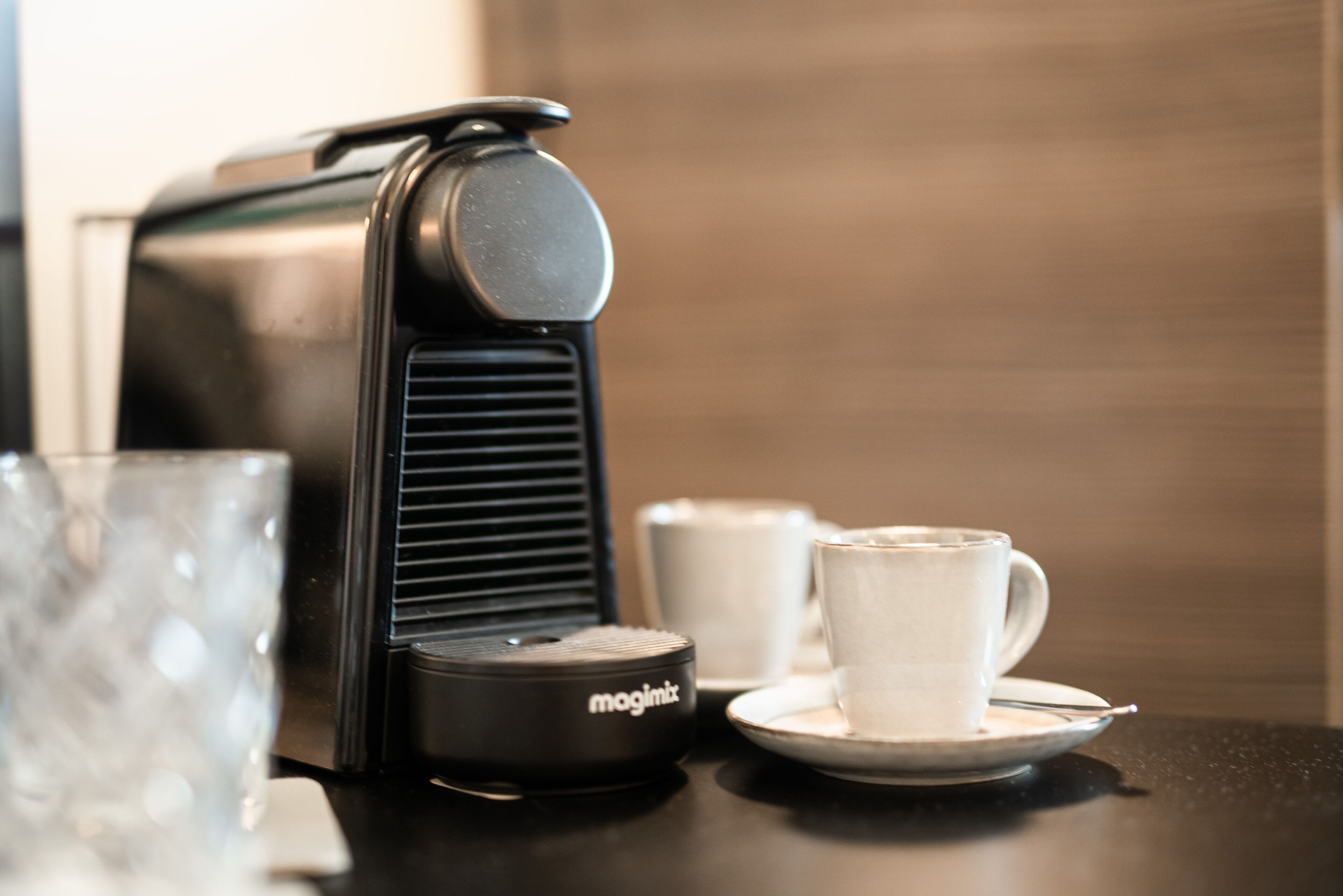 A coffee machine, a cup, and a saucer on a table.