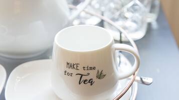 Una taza blanca con su platillo y una bandeja para té con tetera y vasos.
