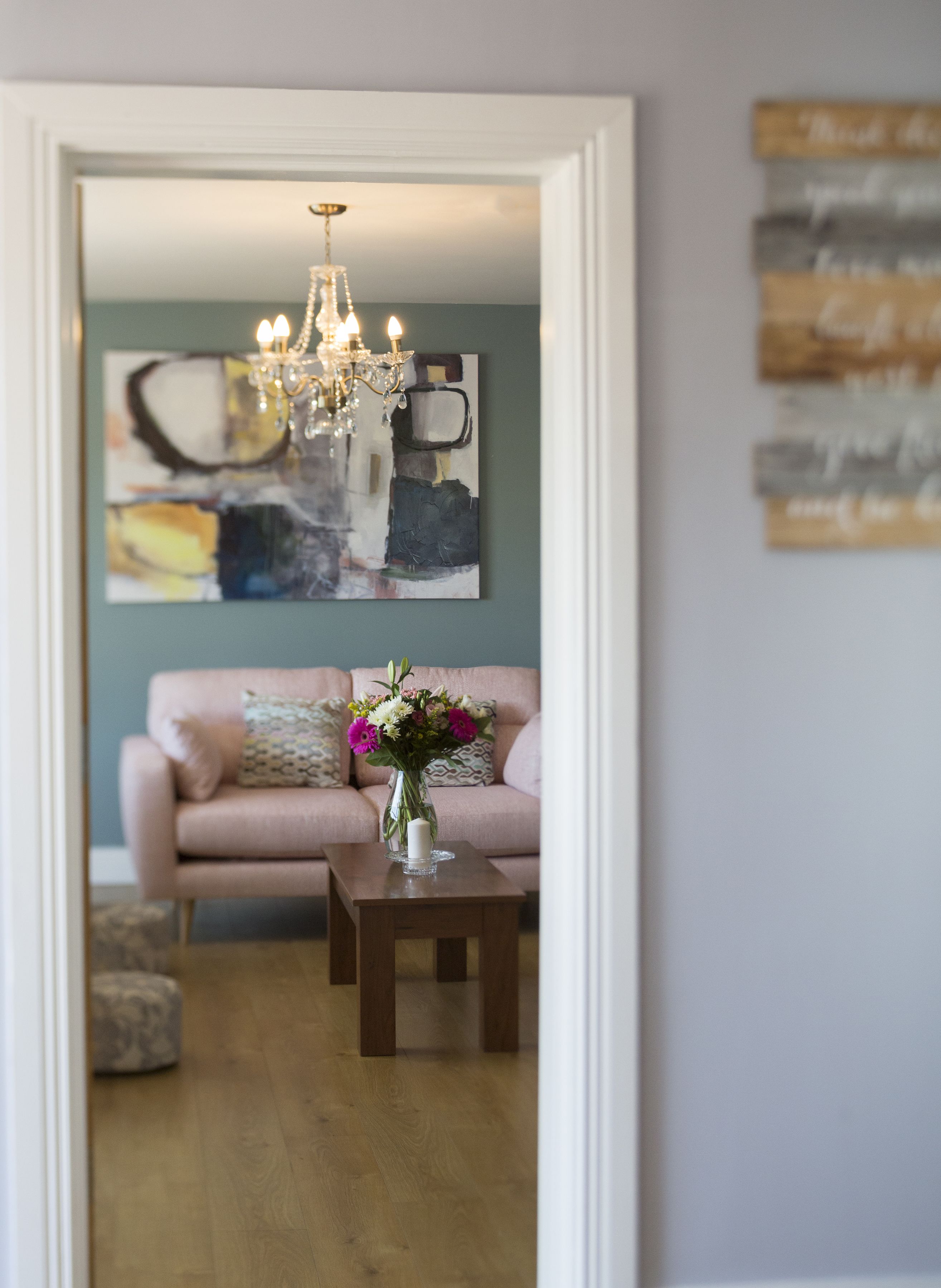 Een woonkamer met een bank, een salontafel en een kroonluchter.