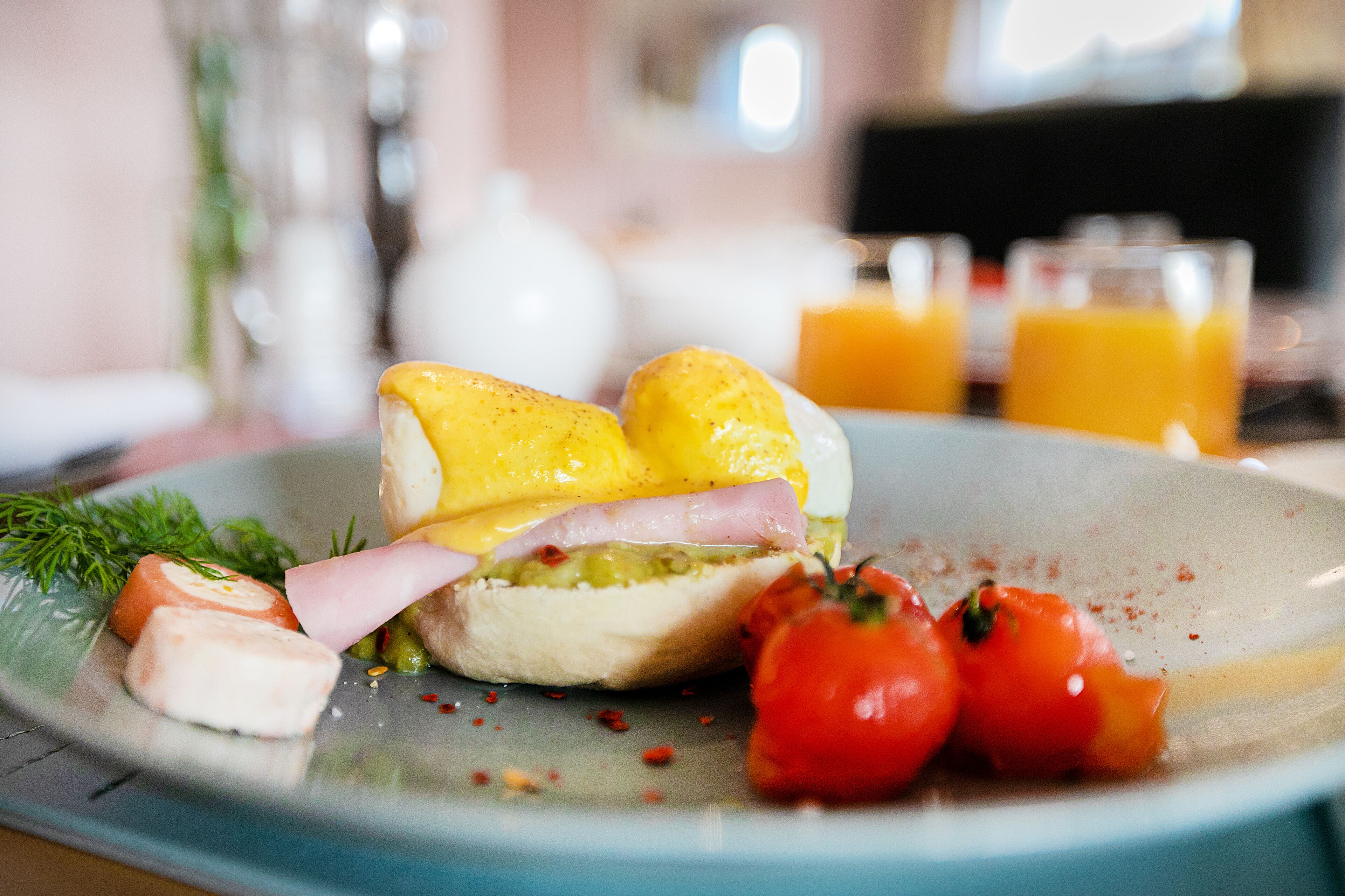 Un plato con un sándwich, tomates y un vaso de jugo de naranja.
