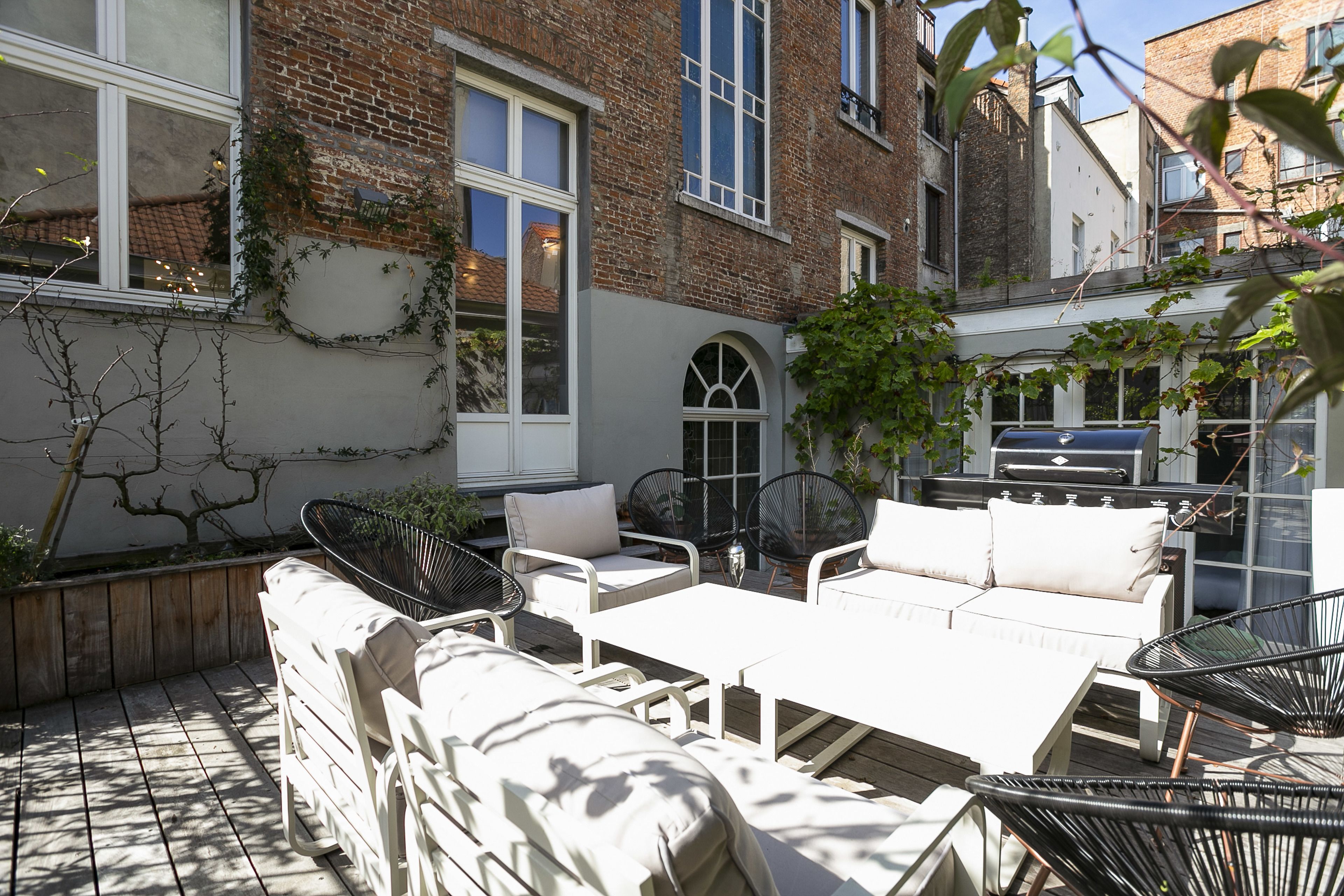 A patio area with outdoor furniture, including a sofa and chairs, a table, and a barbecue grill.