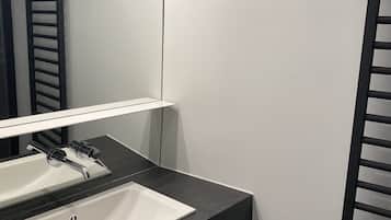 Un baño moderno con un lavamanos blanco, encimera negra y un espejo encima.