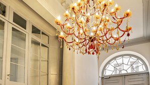 A grand lobby with a large chandelier, a staircase, and a leather sofa. - Fishmarket B&B (Brussels)