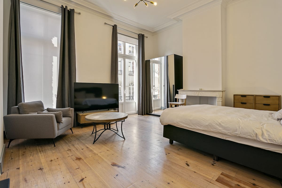 Una habitación de hotel moderna con una cama, un sofá, un televisor y una mesita.