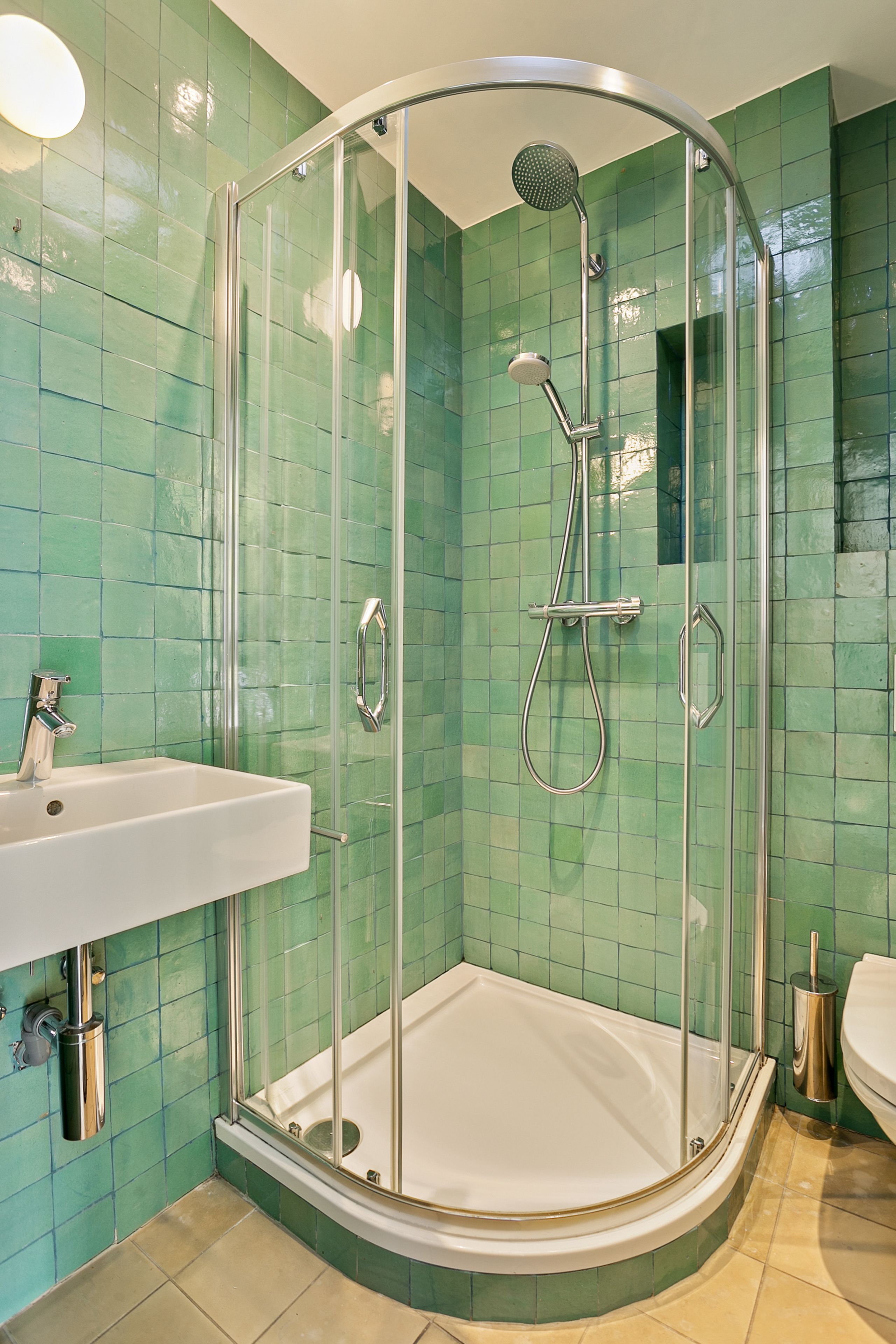 Cabina de ducha con puerta de cristal, lavabo blanco y retrete.