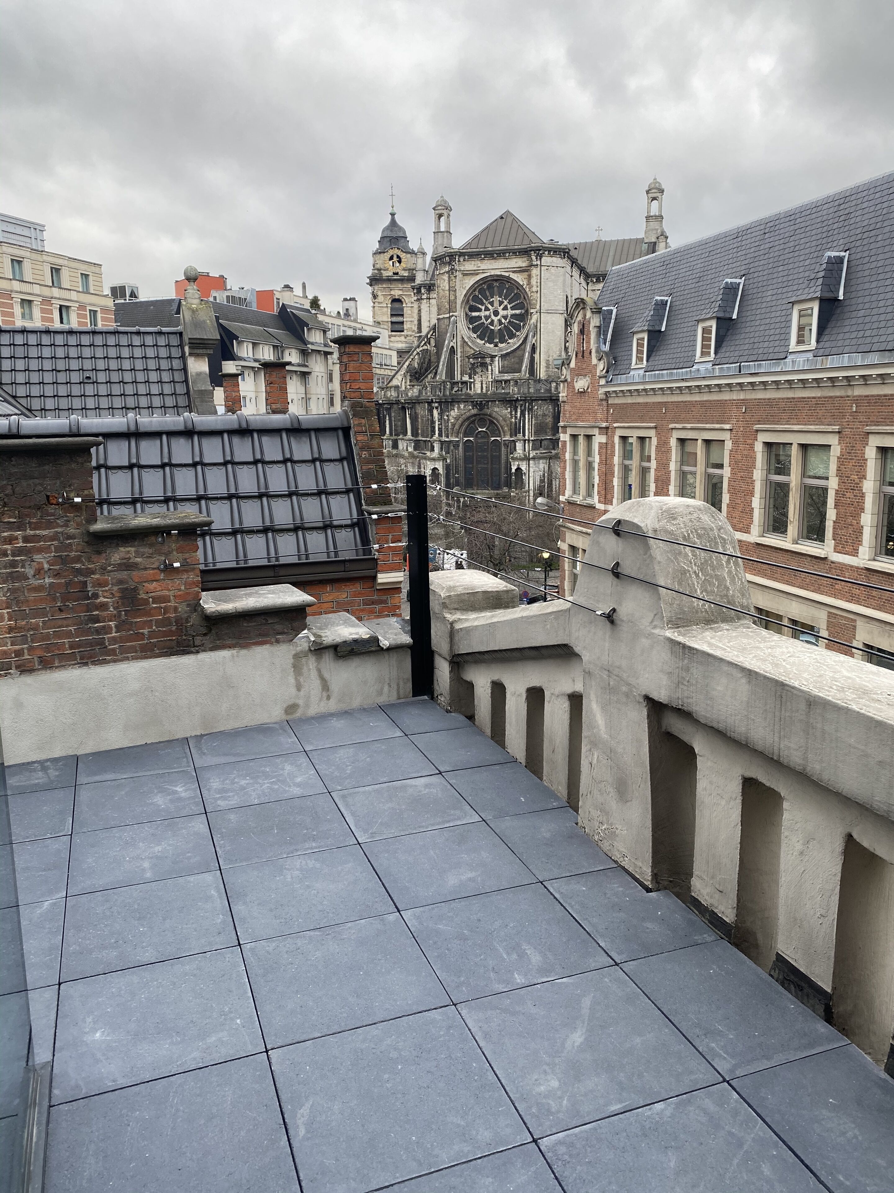 A rooftop terrace with a view of a historic building with a clock tower.