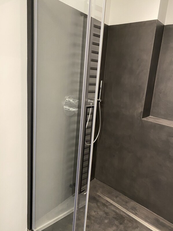 Una ducha moderna con puerta de vidrio, un mando vertical y un panel de control.