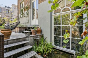 Una terraza de madera con escalones que dan a una ventana con vista a un jardín.