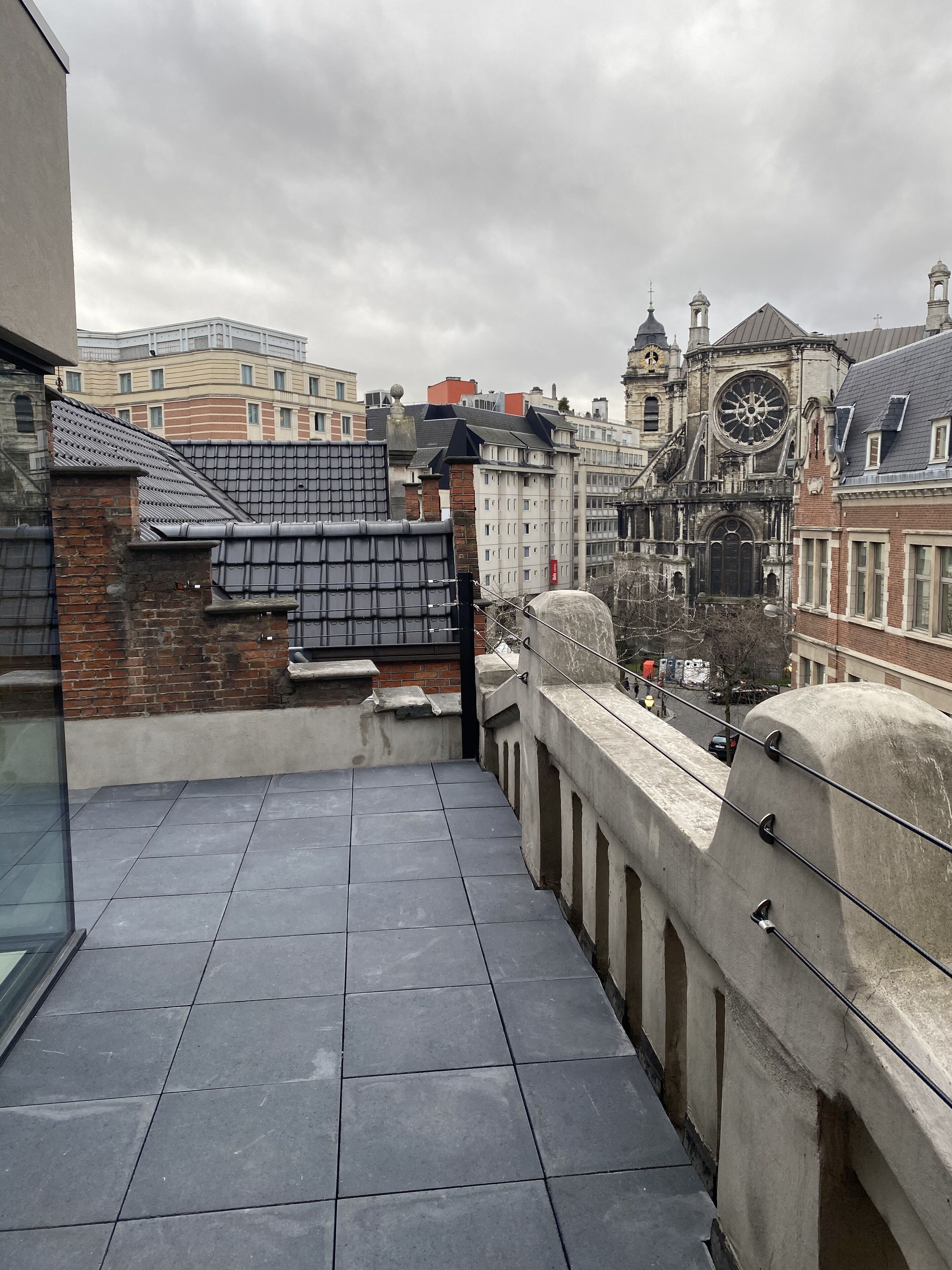 Terraza en la azotea con vistas a edificios históricos, incluyendo una torre del reloj.