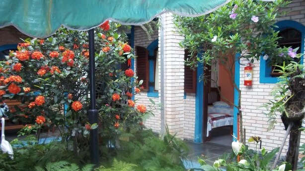 Una habitación con pared de ladrillo, una cama y una ventana con detalles azules.