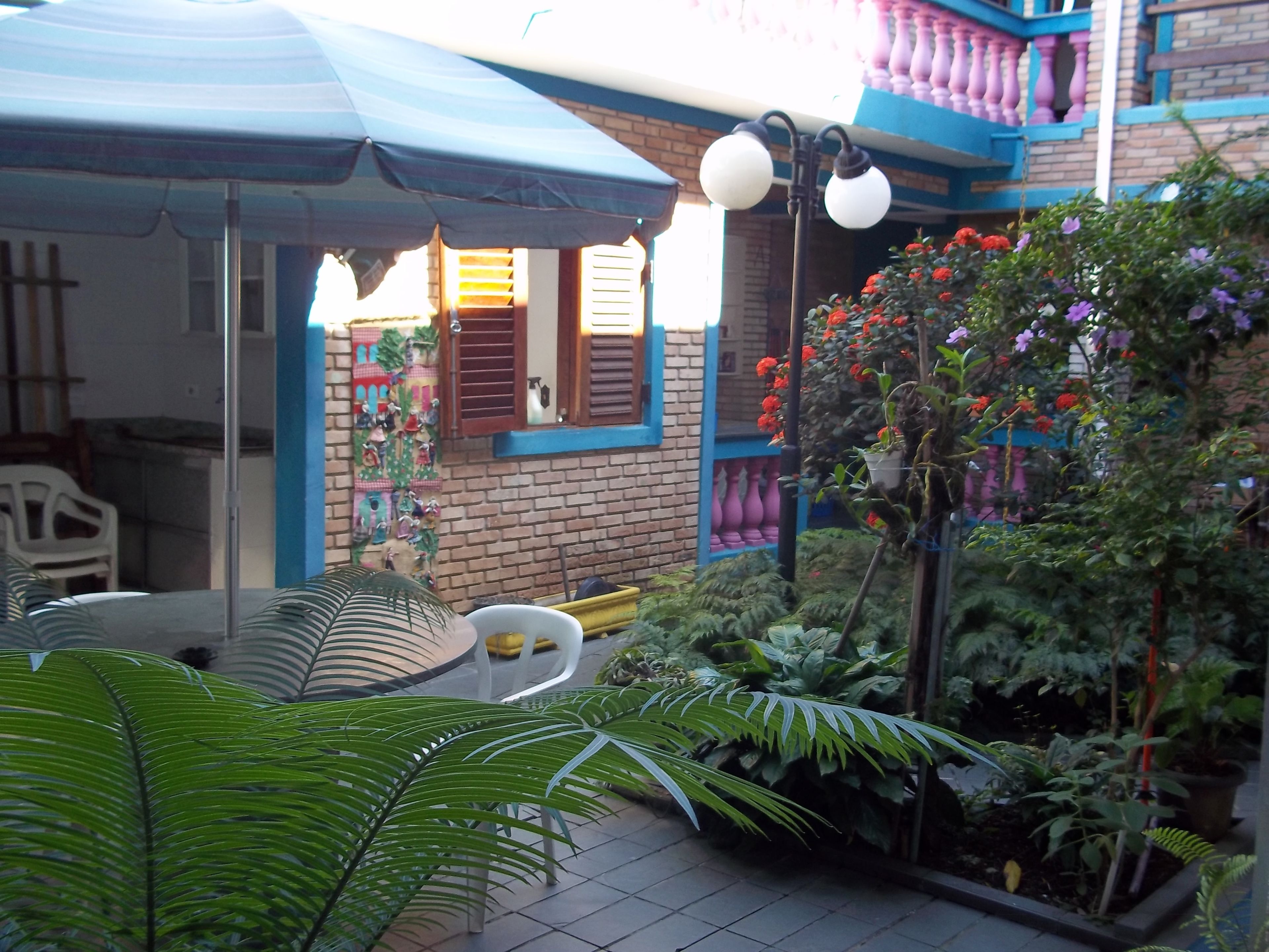 A courtyard with a tiled floor, a covered seating area, and potted plants.