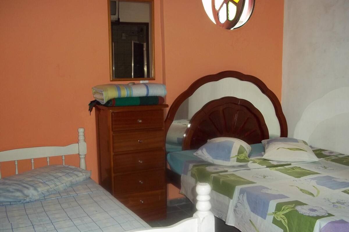 A bedroom with two beds, a wooden dresser, a mirror, and a window.