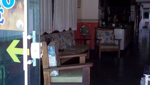 Un salón con sofá, sillones y una mesita. Se observa una zona de cocina al fondo.
