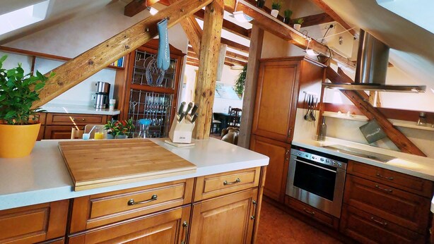 A kitchen with wooden cabinets, a wooden countertop, and a hanging pot rack.