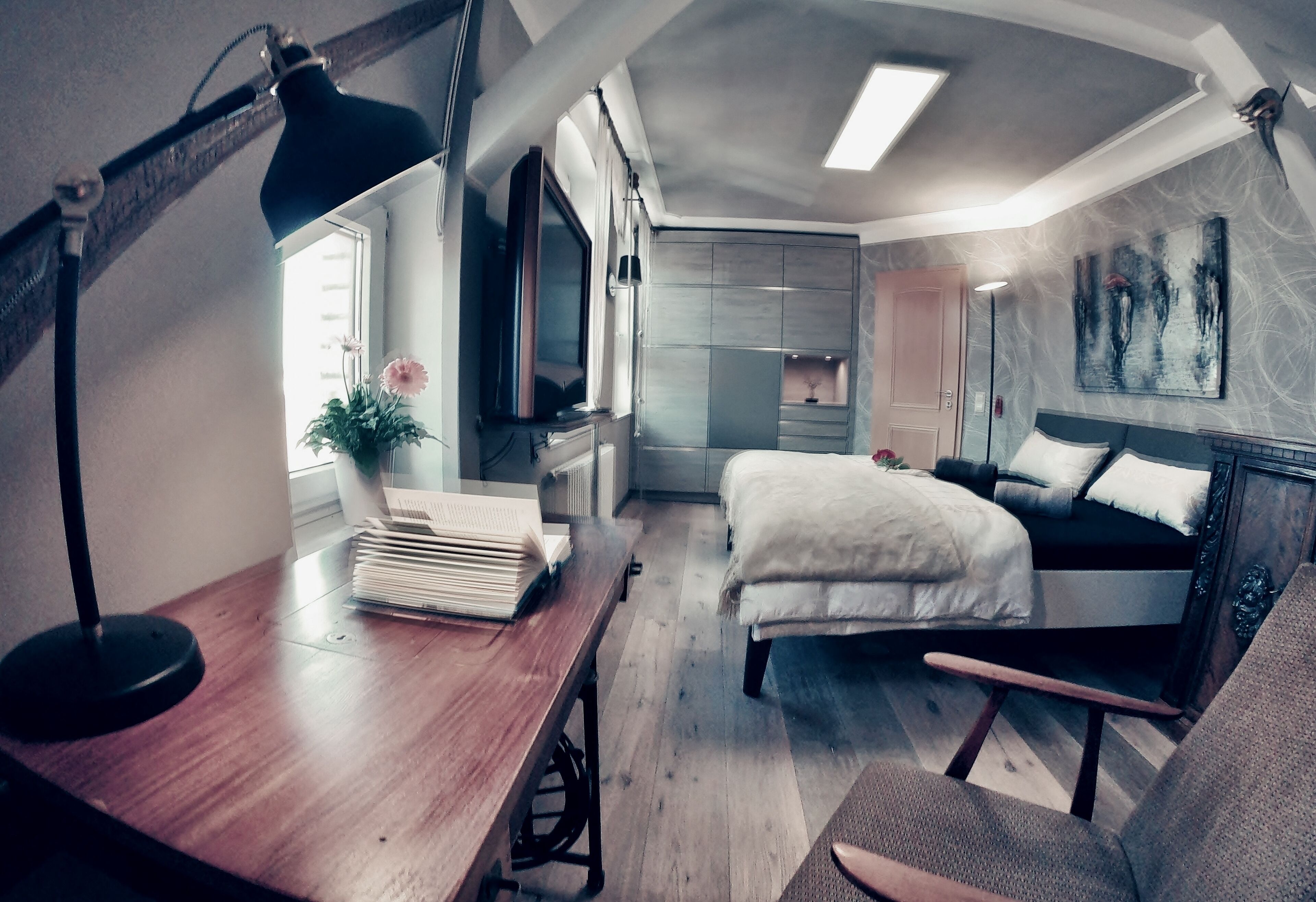 Un dormitorio moderno con una cama, un escritorio, una lámpara y un televisor.