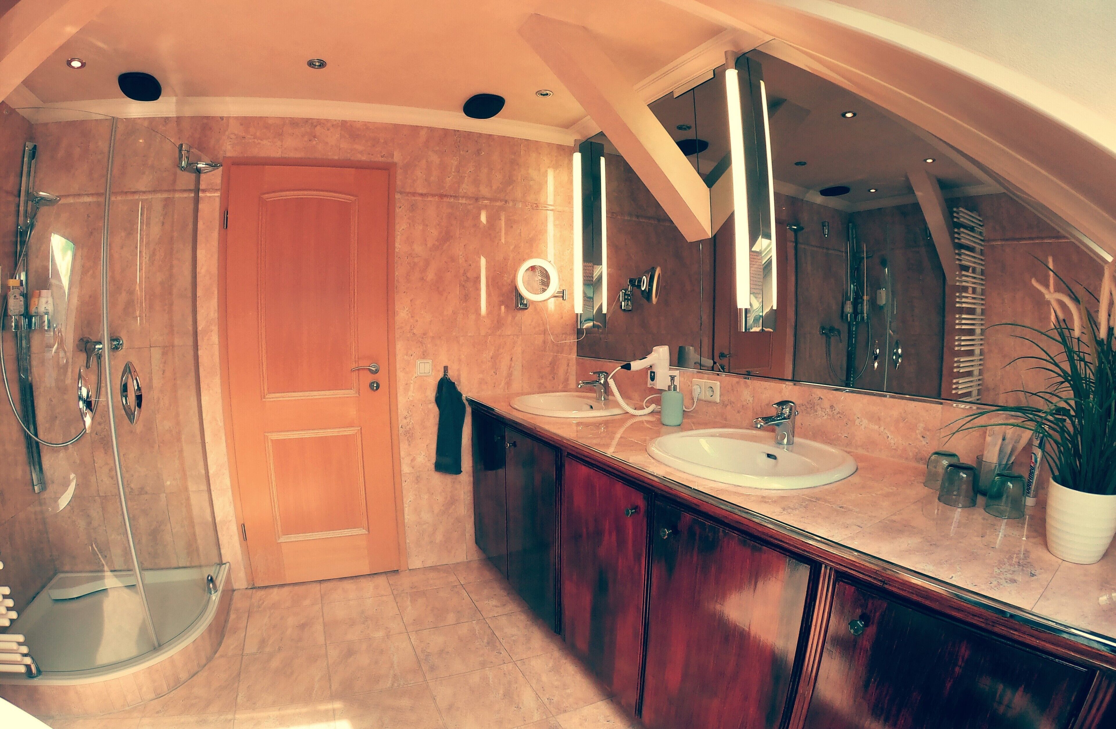 A modern bathroom with a walk-in shower, a large mirror, and a vanity with a sink and countertop.