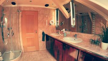 A modern bathroom with a walk-in shower, a large mirror, and a vanity with a sink and countertop.