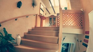 A wooden staircase with a white vase and green plants on the landing.